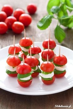 small appetizers with tomatoes and mozzarella are arranged on a white plate