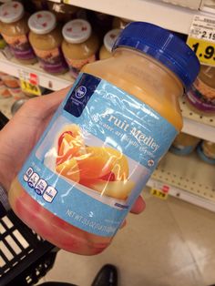 a person holding up a bottle of fruit juice in a grocery store's aisle