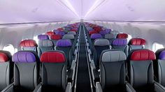 the inside of an airplane with rows of empty seats and red, purple, and blue seats