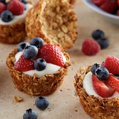 some granola cups with strawberries and blueberries on top