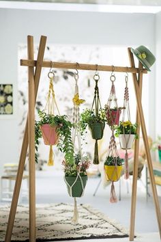 hanging planters with plants in them on a wooden stand