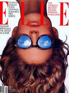 a magazine cover with a woman's face covered in blue goggles and clouds