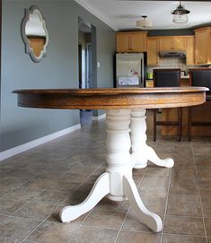 a kitchen with a table in the middle and tile flooring on the other side