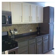 a kitchen with white cabinets and black counter tops