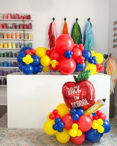 there are balloons in the shape of an apple on top of a desk with school supplies