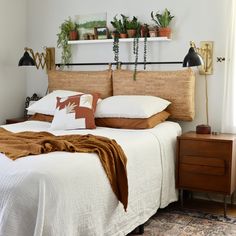 a bed sitting in a bedroom next to a window with potted plants on top of it