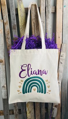 a personalized tote bag sitting on top of a wooden chair with purple flowers