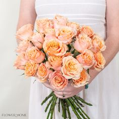 a woman holding a bouquet of peach colored roses