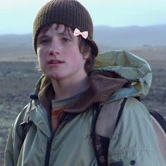 a young boy wearing a hat and jacket with a bow on it's head