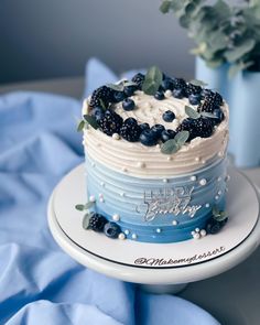 a blue and white cake with berries on top