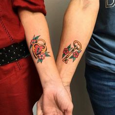 two people holding hands with tattoos on their arms