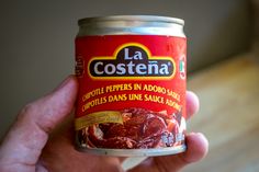 a hand holding a can of food in it's left hand with the label la costena on it