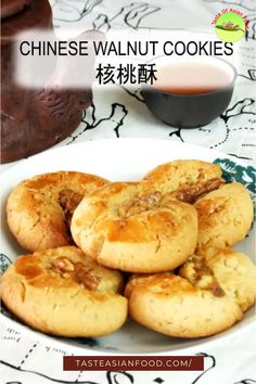 chinese walnut cookies on a white plate with a cup of tea in the back ground