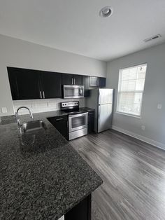 an empty kitchen with granite counter tops and stainless steel appliances