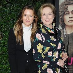 two women standing next to each other in front of a poster