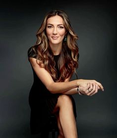 a beautiful woman sitting on top of a chair in front of a black background with her legs crossed