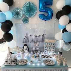 a table topped with lots of desserts and balloons in front of a number five sign