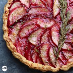 a pie topped with sliced up radishes and rosemary sprig on top