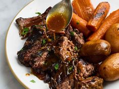 a white plate topped with meat, potatoes and carrots