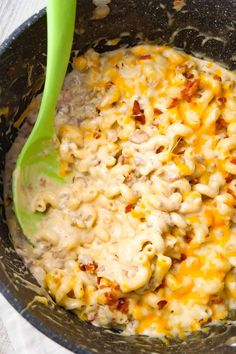 a bowl filled with macaroni and cheese next to a green spoon