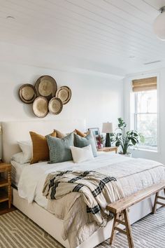 a bedroom with white walls and lots of pillows on the bed