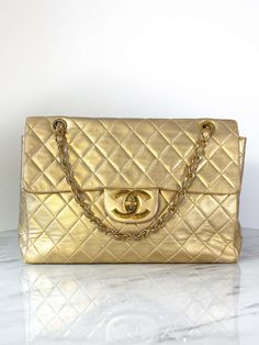 For Sale on 1stDibs - Chanel Jumbo XL Maxi bag in a stunning metallic gold shade, a rare find originating from the 1990s. Crafted from luxurious quilted lambskin leather in Luxury Quilted Gold Bag, Luxury Gold Quilted Bag, Gold Quilted Leather Shoulder Bag, Designer Quilted Gold Shoulder Bag, Gold Quilted Travel Bag, Designer Gold Quilted Shoulder Bag, Designer Quilted Gold Bags, Gold Quilted Formal Bag, Gold Quilted Rectangular Shoulder Bag