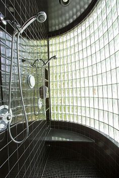 a bathroom with black and white tiles on the walls, shower head and hand held faucet