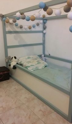 a child's bed with blue and white decorations on the headboard, in a room with tile flooring