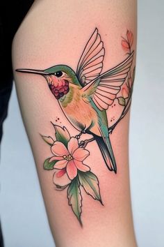 a hummingbird with flowers and leaves on the thigh