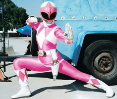 a man in pink and white costume standing next to a blue truck