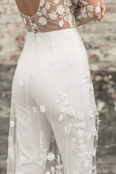 the back of a woman's dress with white flowers on it and sheer sleeves