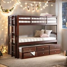 a bunk bed with drawers underneath it and christmas lights on the wall in the background