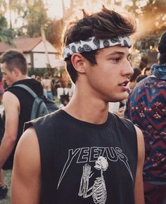 a young man with a bandana on his head standing in front of a crowd