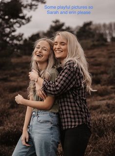 two women hugging each other in the middle of a field with brown grass and trees