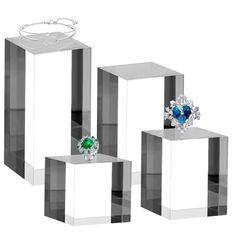 three clear cubes with rings on each one and an emerald ring on the other