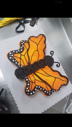 a cake shaped like a butterfly sitting on top of a piece of paper with scissors next to it