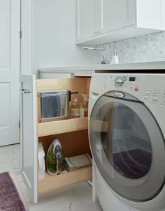 an open washer and dryer in a small room with white cabinets on the wall