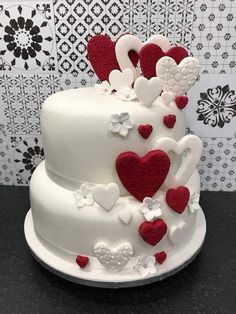 a three tiered cake with hearts and flowers on it