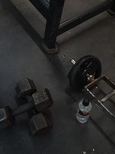 two dumbbells and a bottle of water on the ground next to some metal pipes