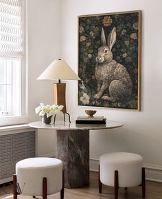 a table with two stools and a painting on the wall