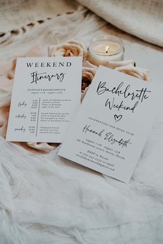 two wedding program cards sitting on top of a bed next to a candle and flowers