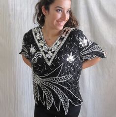 "Straight from the era of disco, this fab little top has so much going on. All over sequins and beads in black and silver. Check out the zig zag design at the bottom and sleeves. 100% silk. Made in India. EXCELLENT vintage condition with no spots, holes or other defects. All sequins appear to be intact. As with all pre-owned clothing, this should be laundered prior to wearing. FITS SIZE M-L Please review the measurements below for an accurate fit. All measurements are taken with the garment laid Vintage Black V-neck Top, Glamorous Sparkling Tops For Evening, Glamorous Sparkling Evening Tops, Vintage V-neck Party Blouse, Vintage V-neck Blouse For Party, Embellished V-neck Party Top, Embellished V-neck Top For Party, Contrast Sequin V-neck Top For Party Season, Sparkling Tops For Evening Party Season