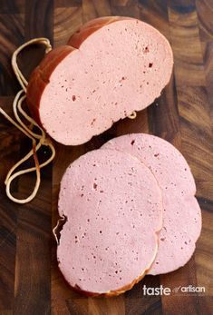 two slices of ham on a wooden cutting board next to a knife and some string