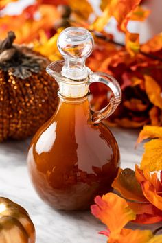 a glass carafe filled with liquid surrounded by fall leaves