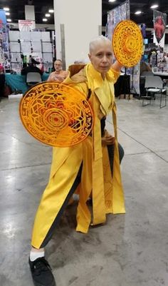 a man in yellow is holding two orange frisbees