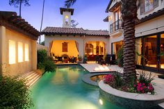 a house with a pool in front of it and palm trees around the pool area