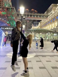 a man and woman are standing in the middle of an open area with lights on