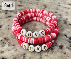 Valentines day bracelets are now here! Snag yours before they are gone. Perfect small gift for friends and family. Beads are placed in a random order and will not be the same pattern as the photo. (same colors will be used: red, pink, light pink and white.) Letters can be changed from black to gold if desired. If not specified then gold letters will be used for set one and black letters will be used for set two. Please specify if you want the bead color different in the personalization box below Small Gift For Friends, Gifts For Valentines, Clay Bead Bracelets, Small Gifts For Friends, Valentines Bracelets, Disc Bracelet, Bracelet Sets, Clay Bracelet, Clay Bead