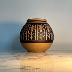 a black and gold vase sitting on top of a white marble counter next to a blue wall