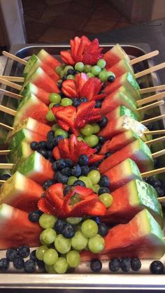 there are many fruits arranged on sticks in the shape of a triangle, with grapes and watermelon